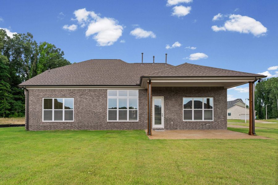Expansive backyard featuring a lush lawn, brick exterior, multiple large windows, and a covered patio with support columns Expansive backyard featuring a lush lawn, brick exterior, multiple large windows, and a covered patio with support columns