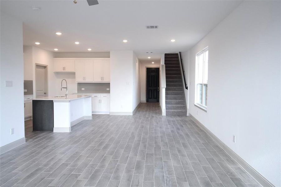 Kitchen featuring visible vents, a sink, open floor plan, white cabinets, and light countertops