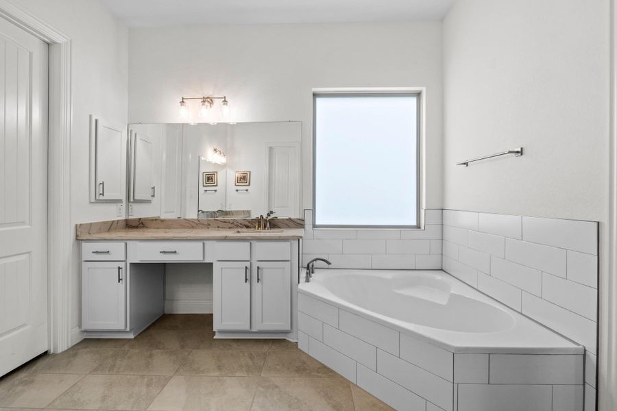 A corner garden tub wrapped in classic white subway tile, perfect for unwinding after a long day.