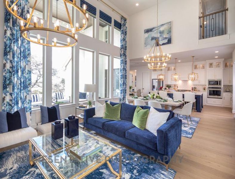 Living room featuring light wood finished floors, an inviting chandelier, a towering ceiling, and recessed lighting Living room featuring light wood finished floors, an inviting chandelier, a towering ceiling, and recessed lighting