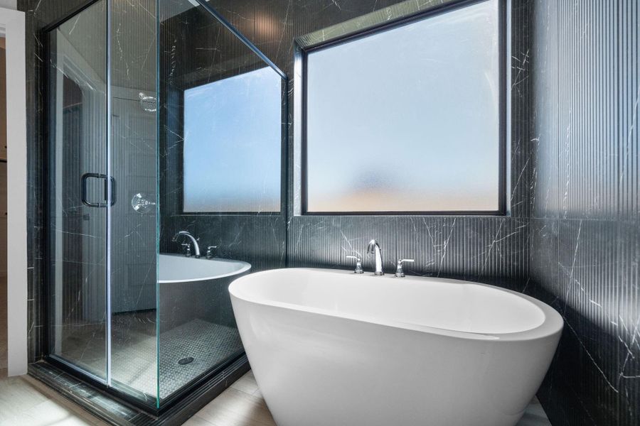 Stunning modern finishes in this main bathroom include a freestanding bathtub surrounding by sleek, black tile to the ceiling. Stunning modern finishes in this main bathroom include a freestanding bathtub surrounding by sleek, black tile to the ceiling.