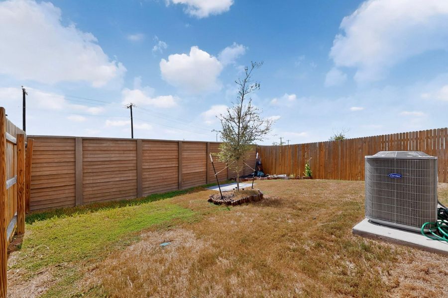 An enclosed backyard area provides a private outdoor space under open blue skies. An enclosed backyard area provides a private outdoor space under open blue skies.