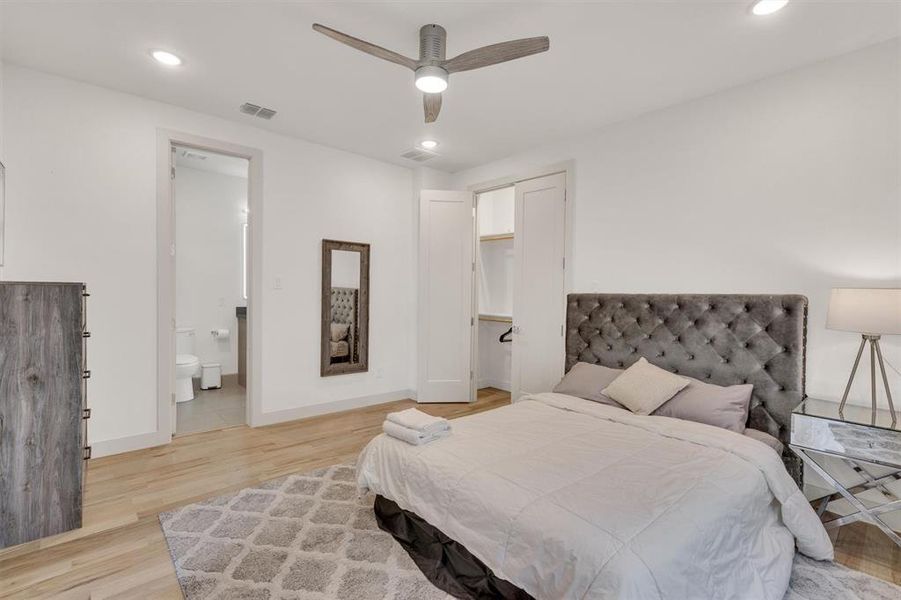 Bedroom with ensuite bathroom, ceiling fan, and light wood-type flooring