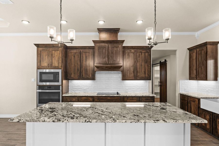 Kitchen featuring crown molding, hanging light fixtures, backsplash, granite countertops, and recessed lighting Kitchen featuring crown molding, hanging light fixtures, backsplash, granite countertops, and recessed lighting