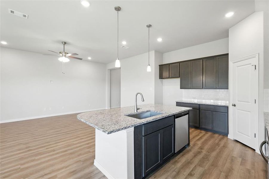 Kitchen featuring light wood-style floors, tasteful backsplash, recessed lighting, light stone counters, and hanging light fixtures