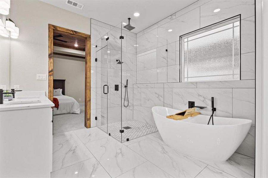 Ensuite bathroom featuring a marble finish shower, a freestanding bath, vanity, recessed lighting, and marble tiled floors