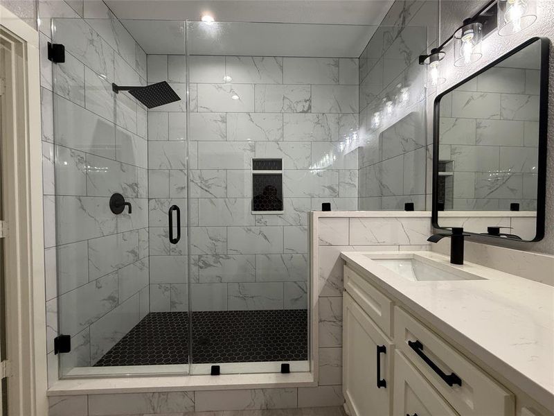 Full bathroom featuring vanity, a stall shower, and marble look tile flooring