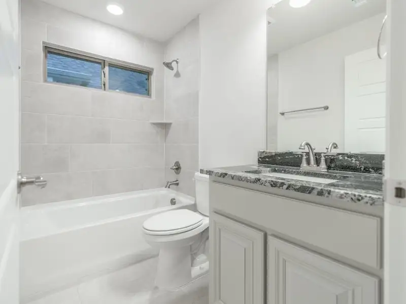 Full bathroom with vanity, tiled shower / bath combo, toilet, and tile patterned flooring