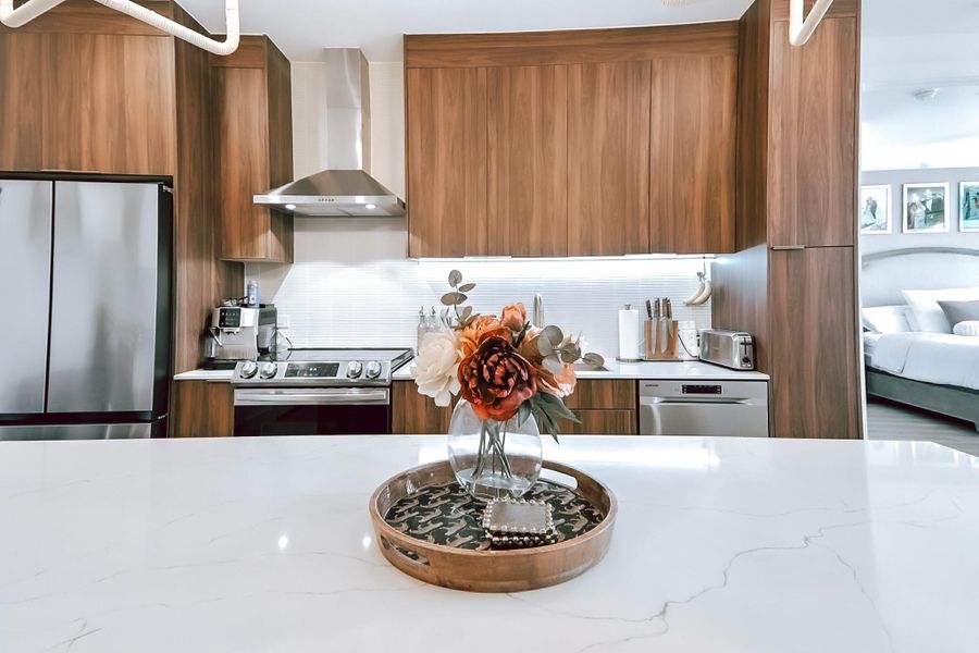 Kitchen featuring modern cabinets, appliances with stainless steel finishes, brown cabinets, and wall chimney exhaust hood