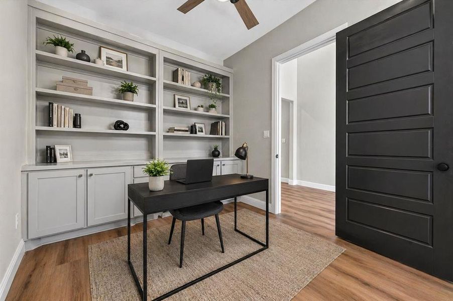 Dedicated space featuring extensive built-in shelving with lower cabinetry, wood-finish flooring, and a modern five-panel interior door