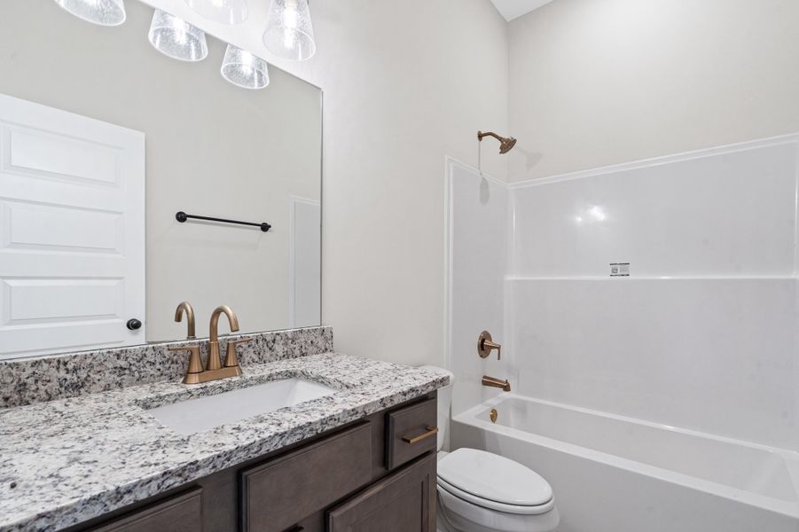 Bathroom featuring a single vanity with a speckled countertop, undermount sink, and bronze-finish faucet