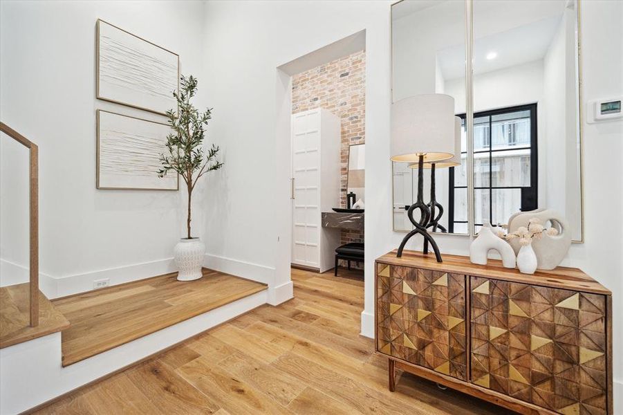 Upon entering the gracious foyer, guests are greeted by the inviting sight of European White Oak flooring leading to the mudroom and central staircase. To the left, an elevator-capable closet stands ready to offer future convenience and accessibility.