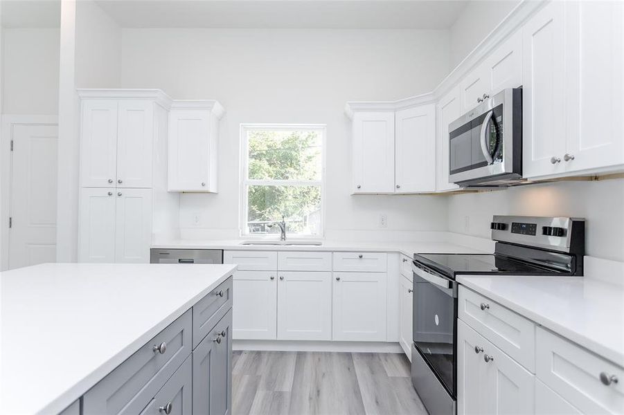 Kitchen featuring white cabinetry, sink, light hardwood / wood-style flooring, and appliances with stainless steel finishes