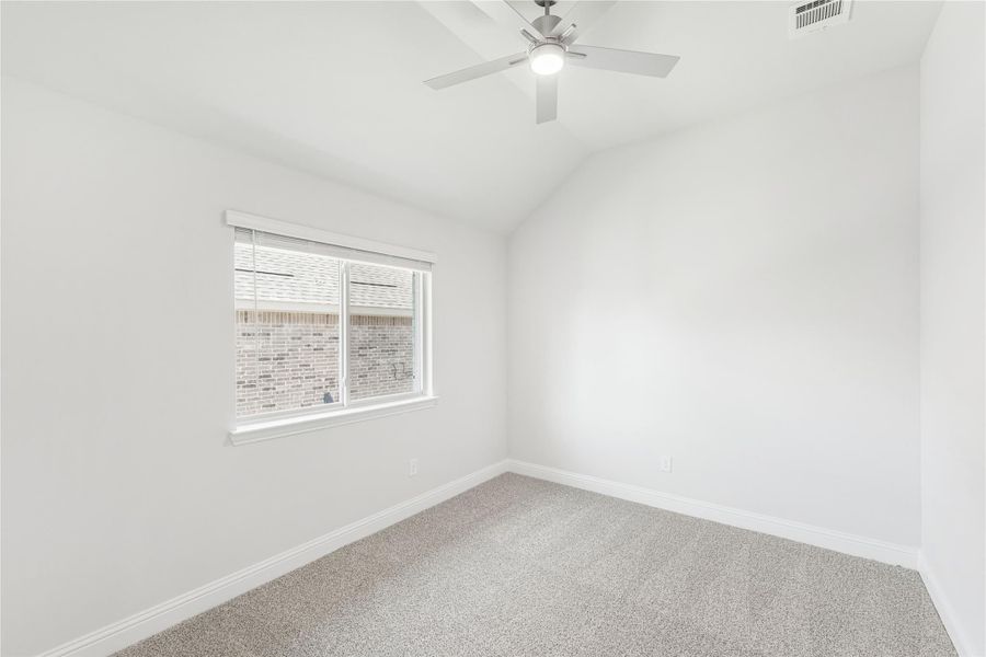 Empty bedroom with vaulted ceiling, ceiling fan, carpet flooring, and single window with blinds Empty bedroom with vaulted ceiling, ceiling fan, carpet flooring, and single window with blinds