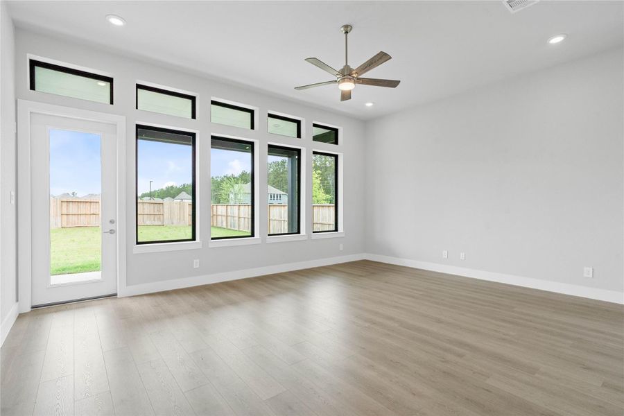 Soaring, tall windows frame the living space, bathing the room in natural light and highlighting the architectural volume of the space. A convenient back door provides direct and easy access to a comfortable covered patio, effortlessly extending your living space outdoors for year-round enjoyment and entertaining.