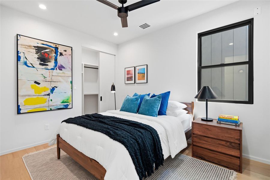 Wood flooring and modern fixtures create a serene retreat in this well-lit bedroom.