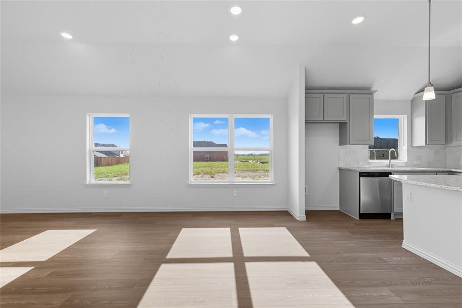 Kitchen with gray cabinets, light wood-style flooring, recessed lighting, dishwasher, and light stone counters Kitchen with gray cabinets, light wood-style flooring, recessed lighting, dishwasher, and light stone counters