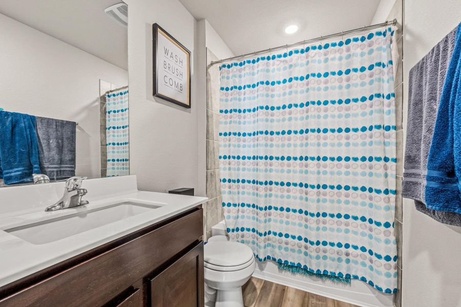A well-lit bathroom features modern fixtures and a practical shower-over-tub combination.