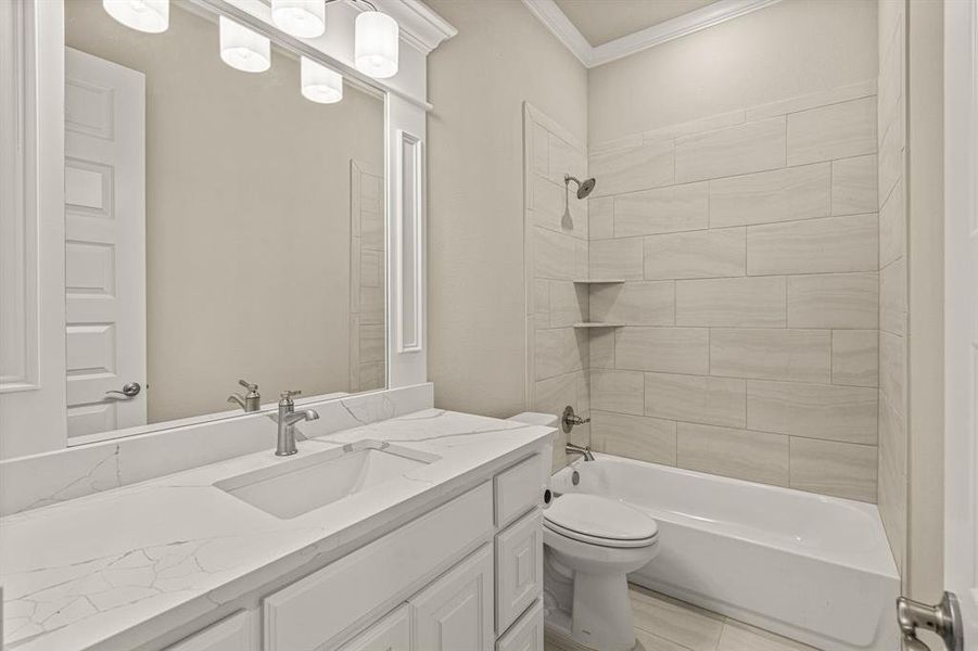 Full bathroom featuring toilet, tiled shower / bath, ornamental molding, and vanity