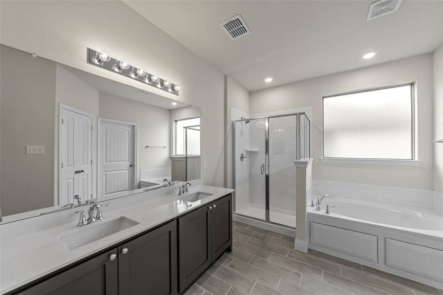 Full bath featuring a garden tub, a shower stall, double vanity, and wood tiled floors Full bath featuring a garden tub, a shower stall, double vanity, and wood tiled floors