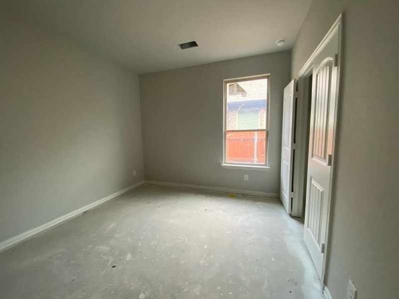Neutral gray wall paint, white trim, a single window, and bi-fold closet doors