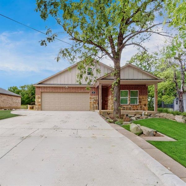 View of front of home with covered porch, a front yard, and a garage