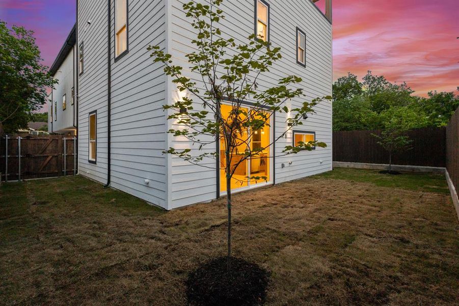 The property features a private yard with a young tree, white siding, and a large sliding glass door