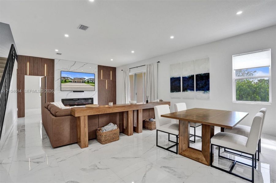 Open-concept living space with large format porcelain tile flooring, recessed lighting, and a contemporary linear fireplace