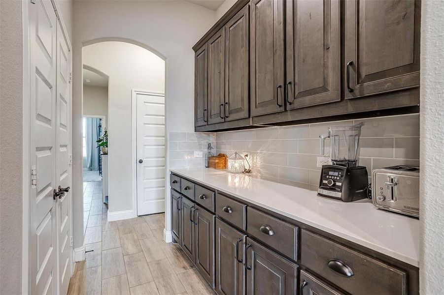 Kitchen featuring dark brown cabinetry and tasteful backsplash