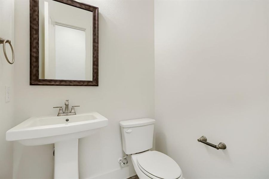 Pedestal sink with chrome faucet, framed mirror, and white wall finishes Pedestal sink with chrome faucet, framed mirror, and white wall finishes