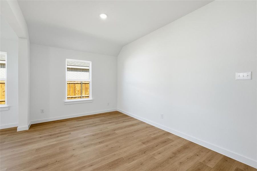 Spare room with lofted ceiling, light wood-type flooring, and recessed lighting