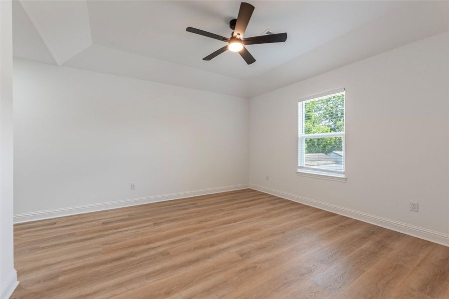 Primary bedroom with laminate flooring and high ceilings.