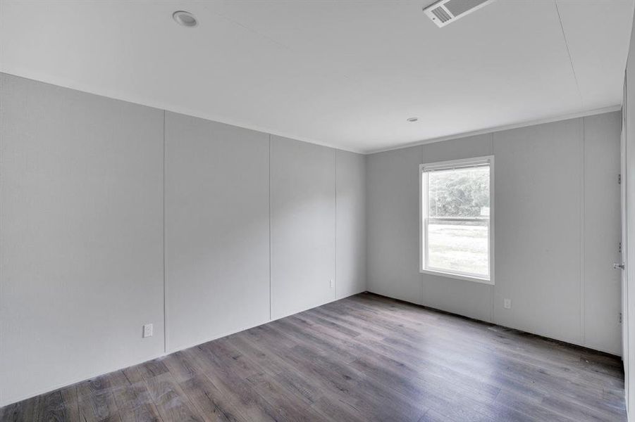 Spacious room featuring wood-finish flooring, light gray wall panels, and white trim