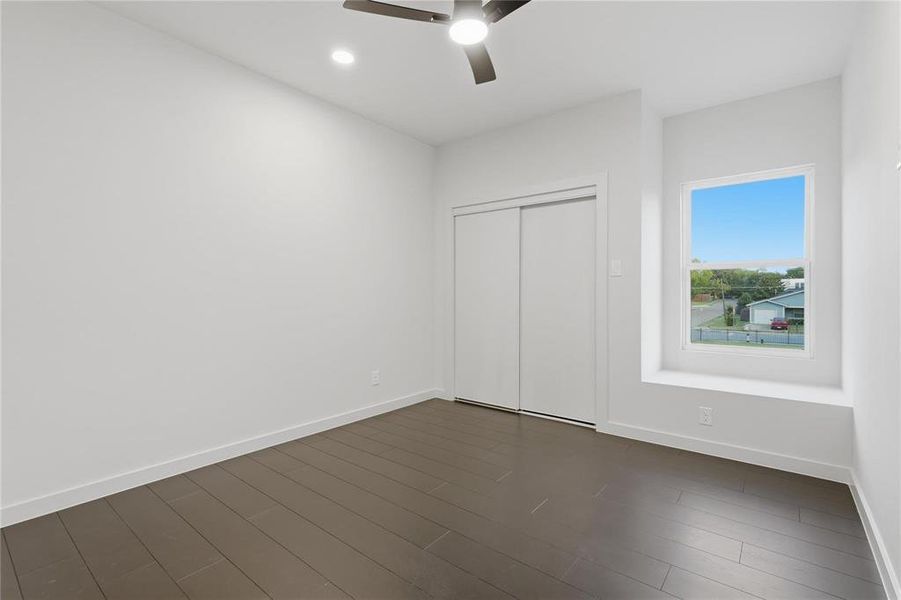 Spacious room featuring dark wood-finish flooring, a contemporary ceiling fan with integrated lighting, a recessed ceiling light, and a built-in window seat