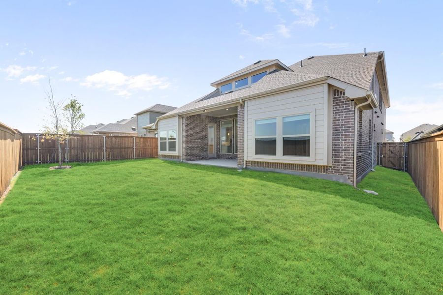 Rear exterior of brick and siding home with large fenced backyard and covered patio Rear exterior of brick and siding home with large fenced backyard and covered patio