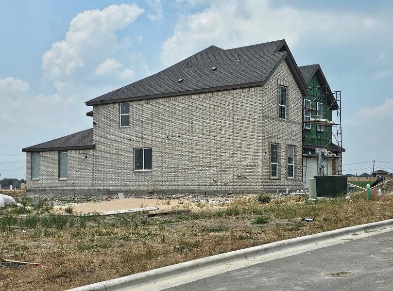 View of home's exterior featuring roof with shingles and brick siding View of home's exterior featuring roof with shingles and brick siding