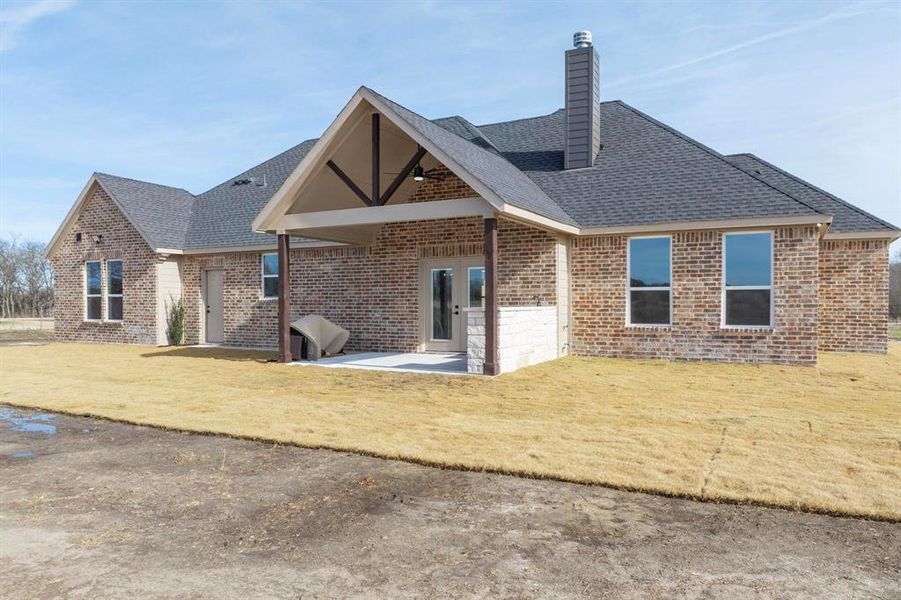 Back of house featuring a lawn and a patio