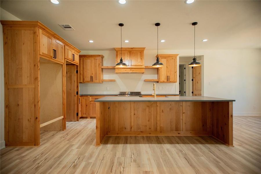 Kitchen featuring visible vents, a kitchen island with sink, recessed lighting, a sink, and light wood-type flooring Kitchen featuring visible vents, a kitchen island with sink, recessed lighting, a sink, and light wood-type flooring