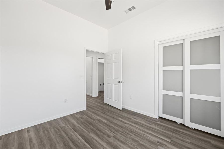 Unfurnished bedroom with dark hardwood / wood-style flooring, ceiling fan, and a closet