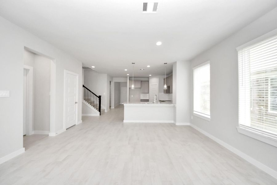 Family room flooded with natural light through the expansive windows.  The premium tile flooring adds a touch of luxury to the space, creating the perfect setting for relaxing moments and cherished gatherings with loved ones. Sample photo of completed home with similar floor plan. Actual colors and selections may vary.