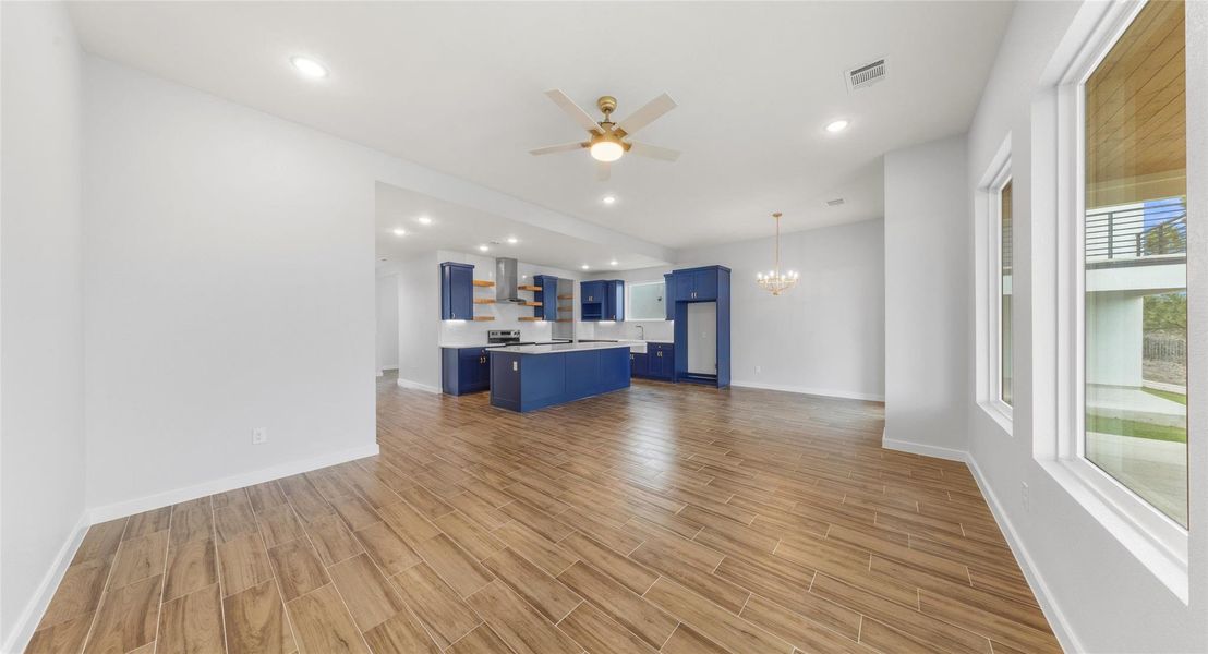 Unfurnished living room featuring wood tiled floors, a chandelier, a ceiling fan, and recessed lighting