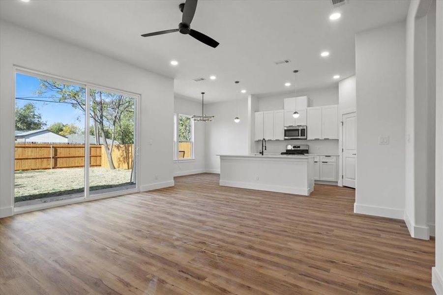 Unfurnished living room featuring recessed lighting, light wood-type flooring, a ceiling fan, and a chandelier