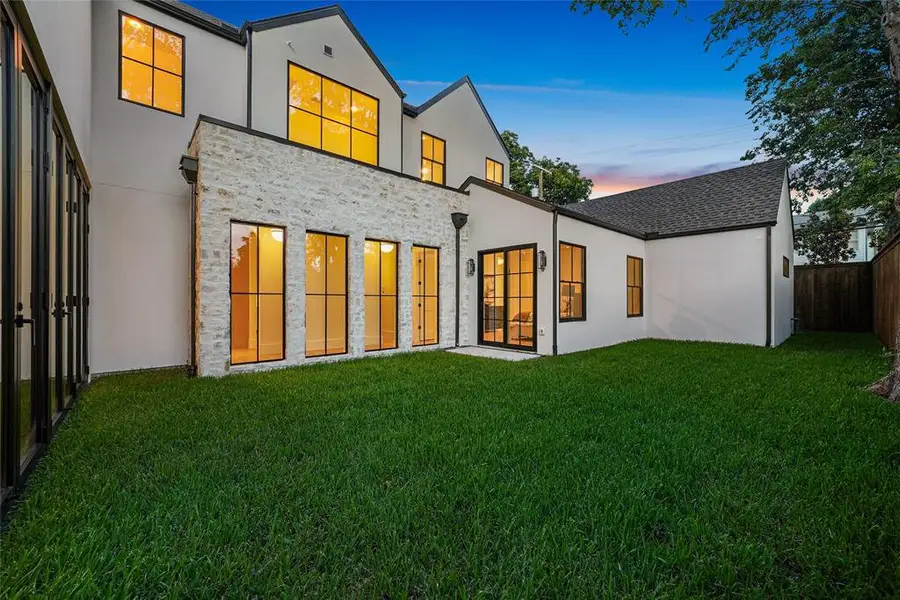 Expansive green lawn bordering a contemporary white stucco and stone-clad exterior