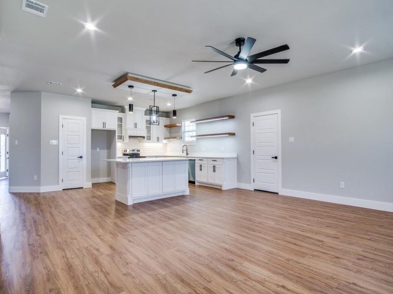 Kitchen featuring a center island, tasteful backsplash, decorative light fixtures, light hardwood / wood-style floors, and white cabinetry