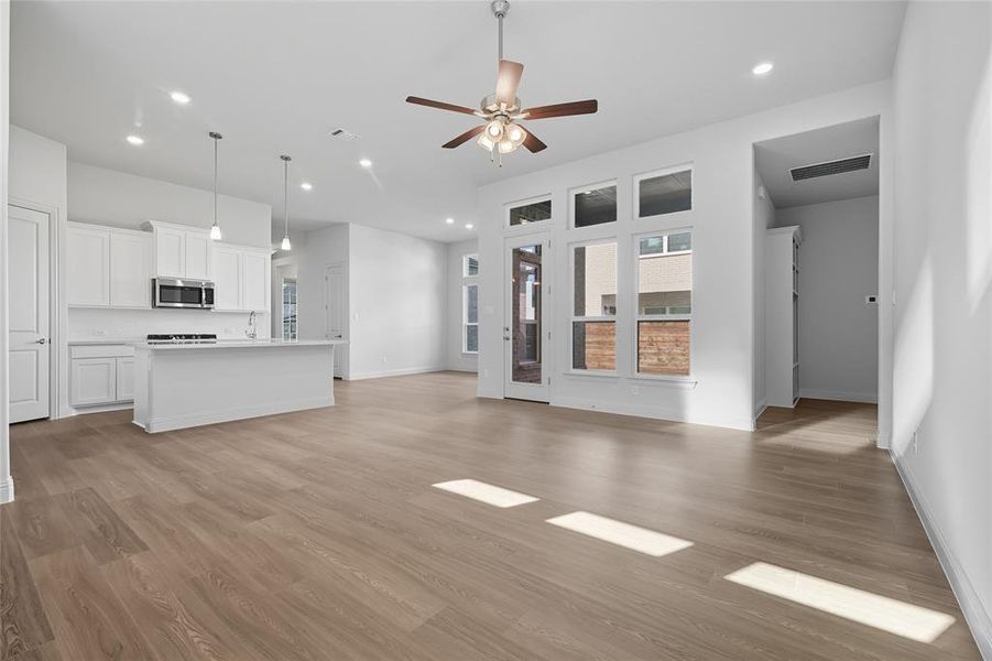 Unfurnished living room featuring light wood-type flooring, a ceiling fan, and recessed lighting