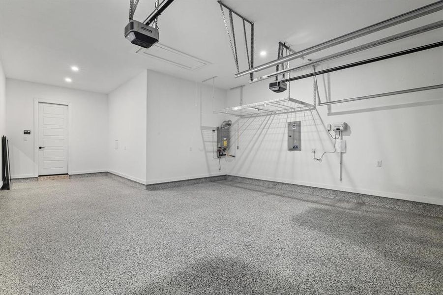 Garage with electric panel, a garage door opener, and recessed lighting Garage with electric panel, a garage door opener, and recessed lighting