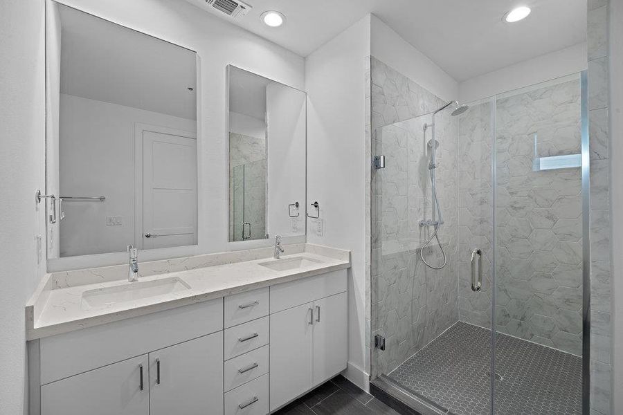 Full bathroom featuring double vanity, a marble finish shower, and recessed lighting Full bathroom featuring double vanity, a marble finish shower, and recessed lighting