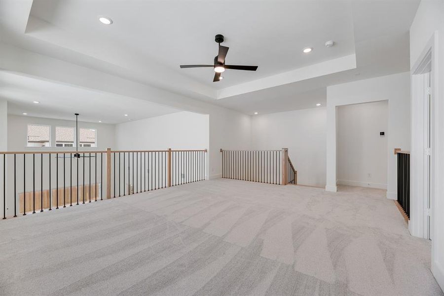 Spare room featuring light carpet, a tray ceiling, recessed lighting, and ceiling fan