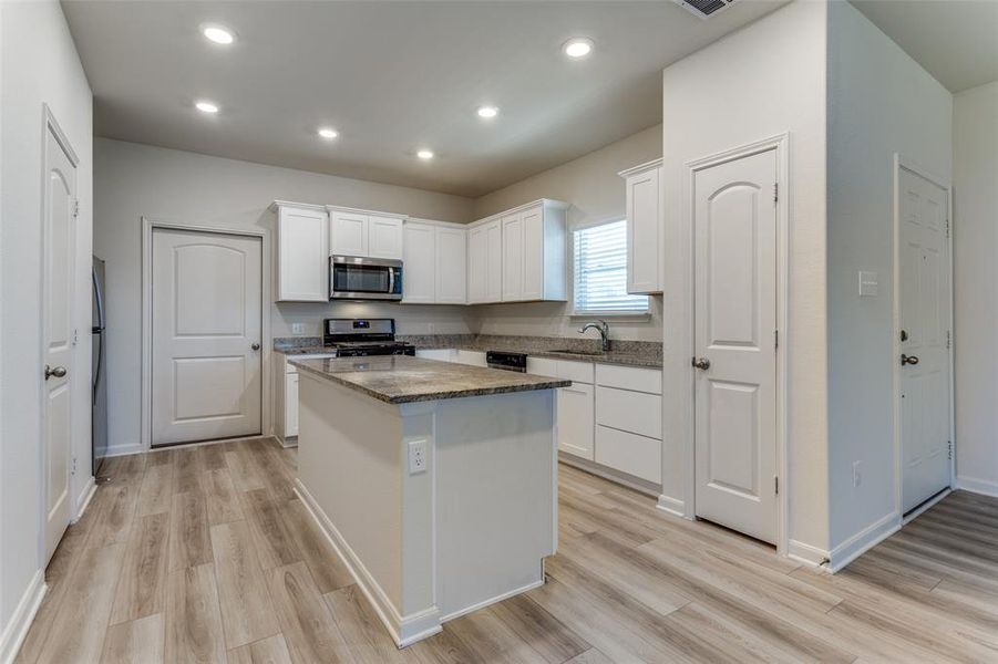 Kitchen featuring white cabinetry, stainless steel appliances, sink, a kitchen island, and light hardwood / wood-style floors