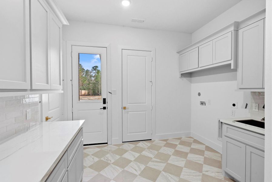 Large utility room with second entry door between the 2 car garage bay and 1 car garage bay